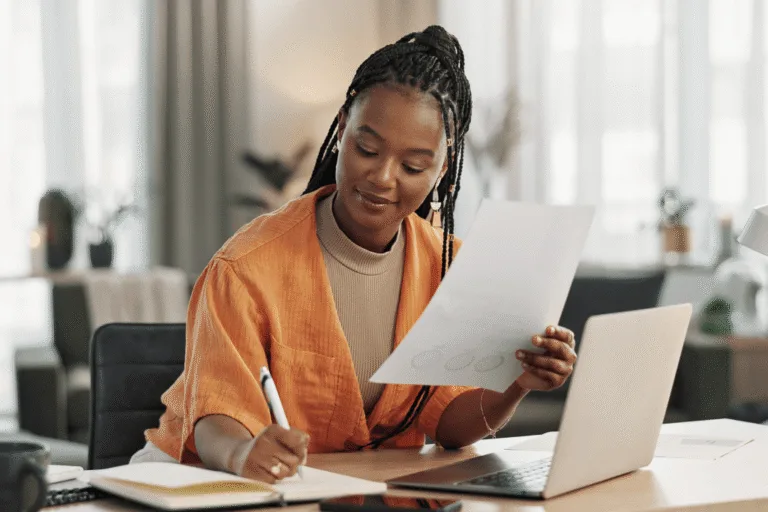 A woman writing notes in a well-lit office.